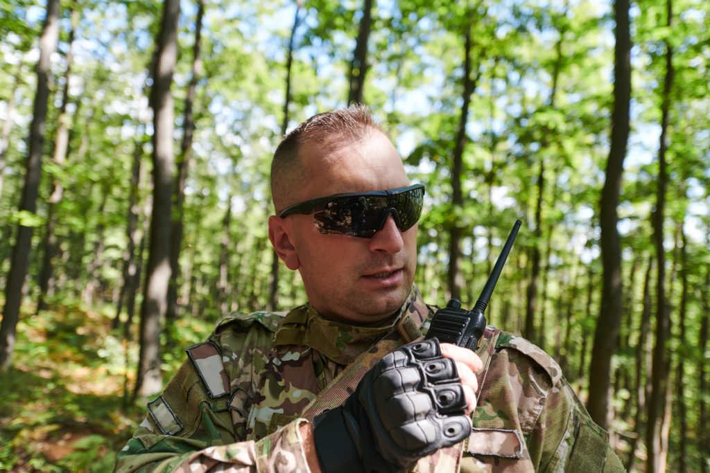 A military major employs a Motorola radio for seamless communication with his fellow soldiers during a tactical operation, showcasing professionalism and strategic coordination.